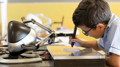 A Cranleigh Abu Dhabi pupil uses a robot to steady his hand during a new trial to improve handwriting. Courtesy: Cranleigh