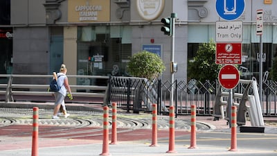 Pedestrians cross the busy tram interchange in Dubai Marina. Pawan Singh / The National
