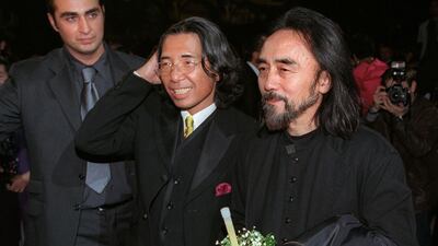 Fashion designer Kenzo, centre, smiles next to fellow Japanese designer Yohji Yamamoto, right, after showing his final collection on October 7, 1999. AFP