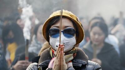 A Chinese woman wearing a mask and sunglasses to protect herself from smog, prays at the Yonghegong Lama Temple in Beijing. Andy Wong / AP Photo