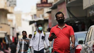 People wearing protective face masks walk in a street of Manama. EPA