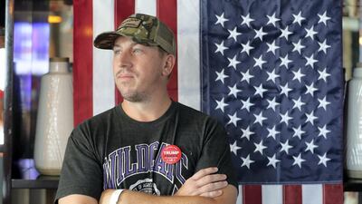 Daniel Edwards, with a Trump pin, watches as the polls come in at Trump International Golf Club.