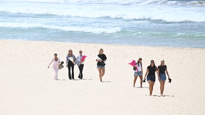 Mourners carrying flowers walk along Bondi Beach. EPA