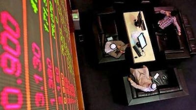 Emirati men sit under a stock market screen at Dubai Financial Market. AFP PHOTO/KARIM SAHIB