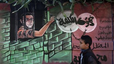 A Palestinian boy walks past a mural depicting Palestinian journalist Mohammed al-Qiq, during a demonstration in Gaza city. Mohammed Abed / AFP