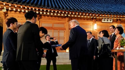 US President Donald Trump receives a copy of an album from members of the K-pop boy band Exo as he arrives for dinner at the Blue House in Seoul. Reuters