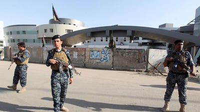 Iraqi policemen stand guard outside a building occupied by a state-owned company that was stormed by militants. Ahmad Al Rubaye / AFP