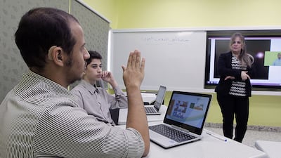 Science teacher Fayrouz Saqr, right, communicates with Grade 8 deaf students using the Smart Learning Programme. Jeffrey E Biteng / The National