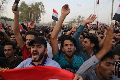 Iraqi protesters wave national flags in front of the provincial council building during a demonstration demanding better public services and jobs, in Basra. AP