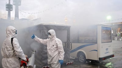 An Iranian medical team uses disinfectant to sanitise vehicles near Imam Reza's holy shrine. West Asia News Agency via Reuters