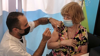 An Israeli health worker gives a third dose of the Pfizer-BioNTech vaccine in Jerusalem's Cinema City complex on Sunday. AFP