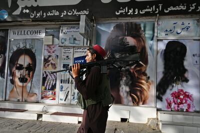 A Taliban fighter passes a beauty salon in Kabala with images of women defaced using spray paint. AFP
