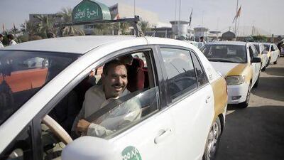 Taxi driver Imran Ali, from Pakistan, picks up a passenger at the Emirates Driving Company in Mussafah. Starting December 31, Abu Dhabi will no longer allow the older gold-and-white taxis on the road. Sammy Dallal/The National