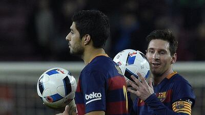 Luis Suarez, left, and Lionel Messi leave the pitch with a match ball each. Lluis Gene / AFP