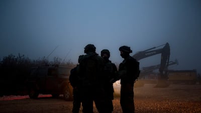 Israeli soldiers stand near the opening of a hole that leads to a tunnel the army says crosses from Lebanon to Israel, near Metula. AFP