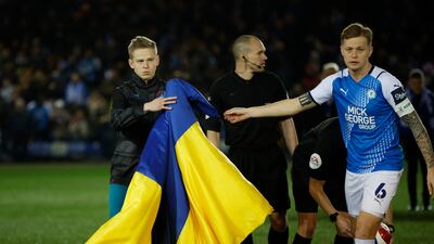 Manchester City's Oleksandr Zinchenko and Peterborough United's Frankie Kent hold a Ukraine flag before their FA Cup encounter. Reuters