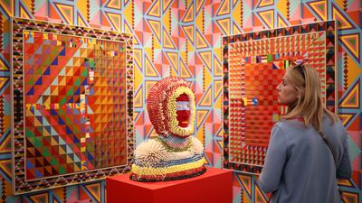 Jeffrey Gibson's intricately patterned paintings and beaded works, set against a patterned wallpaper at the Stephen Friedman booth. Reuters