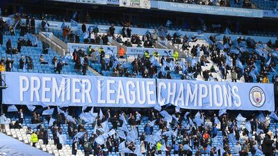 Manchester City fans show their support by holding up a Premier League champions banner at the Etihad Stadium. Getty