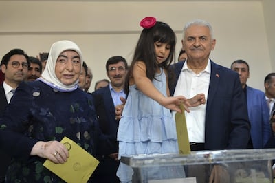 Binali Yildirim, right, mayoral candidate from Turkey's ruling AKP, and his wife Semiha, left, pose for photographers as their granddaughter casts their vote at a polling station in Istanbul. AP