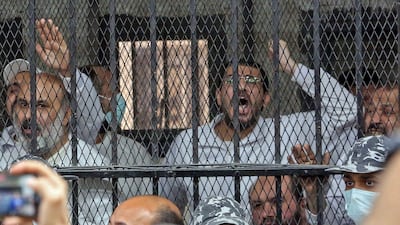 Men charged with illegal excavation and trafficking of antiquities, react in the accused dock during the verdict announcement session of their trial in Egypt's capital Cairo on April 21, 2022. - The court handed Egyptian businessman Hassan Ratib a 5-year jail sentence, and former MP Alaa Hassanein 10 years, local media reported. (Photo by Khaled KAMEL / AFP)