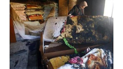 A Palestinian woman holds a burnt mattress as she surveys the damage caused by Jewish settlers throwing a petrol bomb into her house late on Monday night near Nablus, in the West Bank.