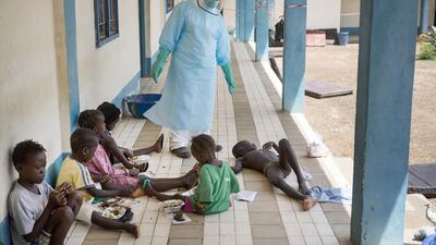 A health official dressed in protective gear examines children suffering from the Ebola virus at Makeni Arab Holding Centre in Makeni, Sierra Leone, on Saturday. Tanya Bindra / AP Photo