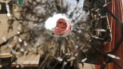 A boy is pictured through a bullet hole in a window of the building where suspected militants were hiding out in the Jordanian village of Garifla, near the southern city of Karak, on December 21, 2016. Muhammad Hamed/Reuters