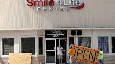 People at a business in the Normandy area in Miami Beach, Fla., remove the plywoods used as shutters covering the front windows Saturday, Aug. 31, 2019, as Hurricane Dorian's latest track shows the storm has shifted east and north, increasing the possibility that the storm would not make landfall in the state of Florida. (Pedro Portal/Miami Herald via AP)