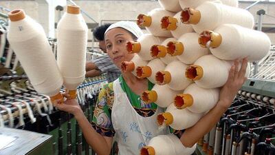 A worker carries yarn at a textile factory in Hefei, China. A drop in demand for Chinese products could dampen the global recovery.