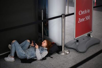 A passenger lies on the floor at London Stansted Airport as airlines warned travellers to check their flight's status before leaving home. AFP