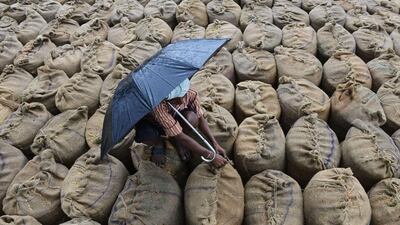 Indian farmer Mekhala Anjaneyulu seals wet bags of unpolished rice to be dried after unseasonal overnight rains soaked the area at the Agriculture Market Yard at Jangaon Mandal of Warangal District, about 85 kms from Hyderabad. Noah Seelam / AFP