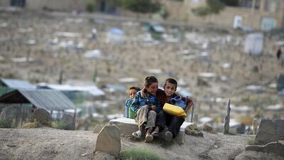 Afghan children sit on a tomb in a cemetery outside the Kart-e-Sakhi shrine in Kabul. Jose Cabezas / AFP Photo