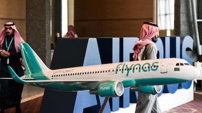 Saudis walk past a model of a Flynas plane during a ceremony for the signing of an agreement with European Airbus, on January 16, 2017 in the capital Riyadh. Low-cost Saudi carrier flynas on Monday signed an $8.6 billion deal with European plane manufacturer Airbus to purchase 80 A320neo single-aisle jets. / AFP PHOTO / FAYEZ NURELDINE
