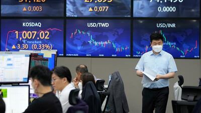 A currency trader passes by screens showing foreign exchange rates at the KEB Hana Bank headquarters in Seoul, South Korea. Asian shares mostly rose on Friday, as investors digested the latest message from the US Federal Reserve on raising short-term interest rates by late 2023. Photo: AP