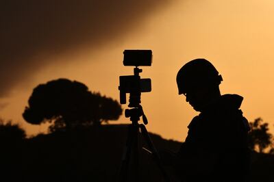A member of the media stands behind his camera at a spot overlooking the Gaza Strip in the southern Israeli city of Sderot on October 26, 2023. AFP