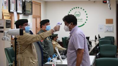 A man wearing a protective mask has his body temperature reading taken upon arriving at the police station in Naif. AFP