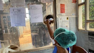 A medical worker checks a person's temperature at the Matanda Hospital in Butembo, where the first case of Ebola died, in the North Kivu province of Congo, February 11, 2021. AP Photo