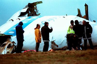 Unidentified crash investigators inspect the nose section of the crashed Pan Am flight 103, a Boeing 747 airliner in a field near Lockerbie, Scotland, Dec. 23, 1988. AP