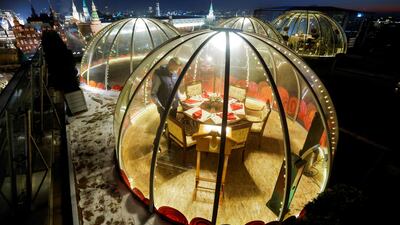 A waiter sets a table inside a transparent pod offered for private Christmas meals with the backdrop of the Kremlin and Red Square on the rooftop of Ritz-Carlton hotel in Moscow, Russia. REUTERS