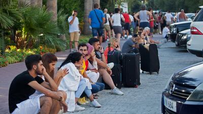 Guests of the Acapulco hotel in Kyrenia (Girne) in the self-proclaimed Turkish Republic of Northern Cyprus (TRNC) north of the divided Cypriot capital Nicosia, stand outside with their belongings after the building was damaged when a military depot exploded nearby, on September 12, 2019. Multiple explosions at a Turkish military base in northern Cyprus damaged a hotel in a neighbouring holiday resort early Thursday, prompting the evacuation of terrified tourists, officials said. / AFP / Birol BEBEK