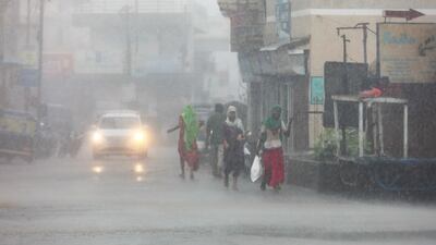 People walk on a street during heavy rain in Mandvi in the western state of Gujarat, India, as Cyclone Biparjoy makes landfall. EPA