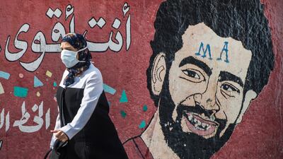A woman wearing a protective mask walks in front of a mural depicting Liverpool's Egyptian striker Mohamed Salah in Cairo, Egypt, 25 March 2020. Egyptian authorities announced a two-week curfew, starting from 25 March, during which public transportation will be suspended to avoid the spread of coronavirus. EPA