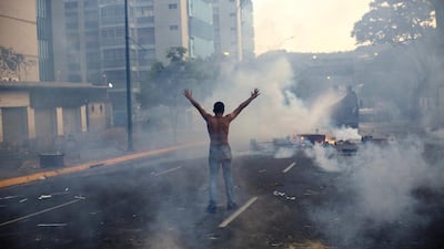 A demonstrator raises his arms toward the Bolivarian National Police as they fired tear gas and a water canon on February 19, 2014, in the Altamira neighbourhood of Caracas, Venezuela. National security forces dispersed anti-government demonstrators who tried to block the city’s main motorway on Wednesday evening. Rodrigo Abd / AP photo