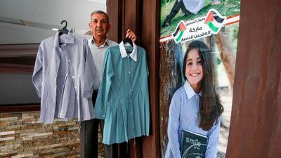 A factory manager holds up a newly-sewn uniform. AFP