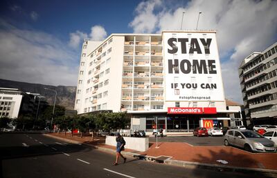 A man walks past a poster covering the side of a building ahead of a 21-day lockdown aimed at limiting the spread of Covid-19 in Cape Town. Reuters