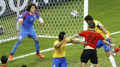 Brazil's Thiago Silva, right, heads the ball but fails to get it past Mexico's Guillermo Ochoa, left, during their 2014 World Cup Group A soccer match at the Castelao Arena in Fortaleza on June 17, 2014. Mike Blake / REUTERS