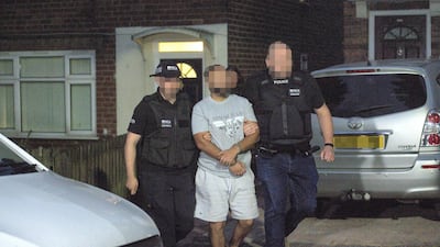 A man is led away by officers from a home in Birmingham, UK, after an investigation linked to EncroChat. PA
