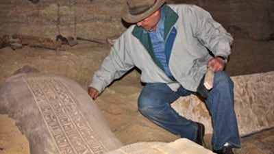 Egypt's top archaeologist Zahi Hawass examines a newly-discovered Egyptian mummy in a sarcophagus in a tomb at Saqqara, south of Cairo.