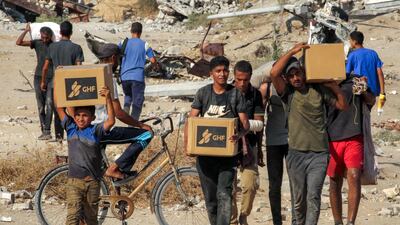 Palestinian boys collect aid from a GHF food bank in central Gaza. AFP