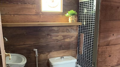 The wood-clad bathroom has a sink and electric shower